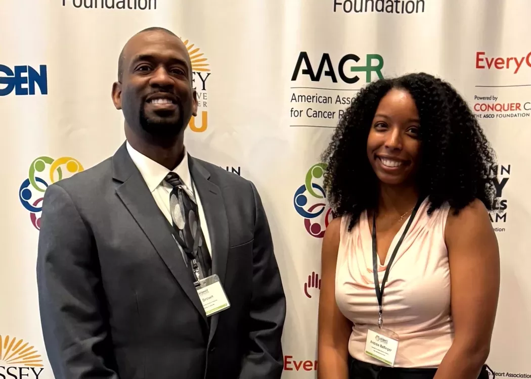 Two students standing in front of logo wall.