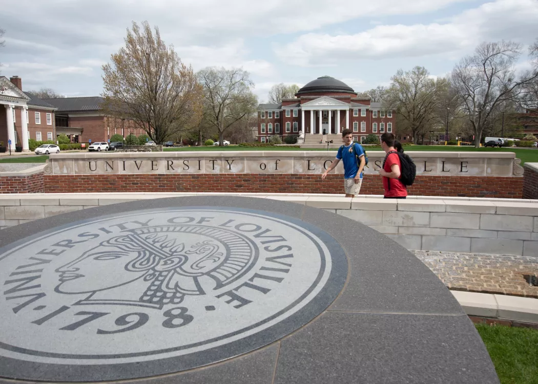 Students walking and talking near the 3rd Street entrance with Grawemeyer Hall and the School of Law buildings in the background
