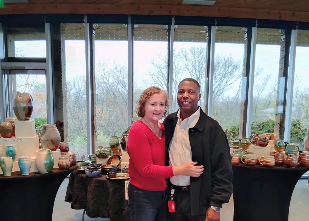 A photo of Tonya Johnson and her partner standing in front of her pottery