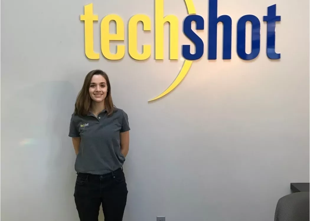 Hannah Meriwether posing next to the sign for TechShot during her co-op there.