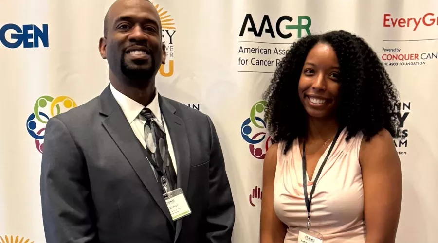 Two students standing in front of logo wall.