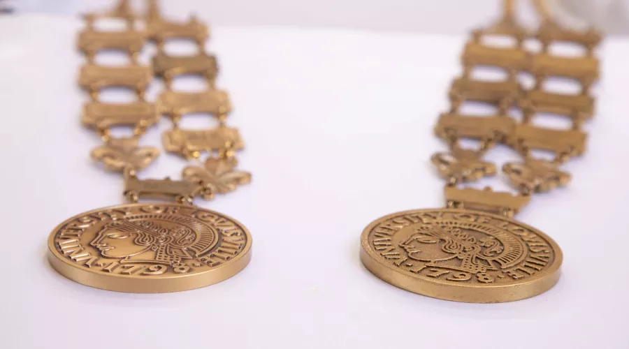 The original metal medallion worn by UofL’s president (left) and the lighter weight 3D printed replica (right).