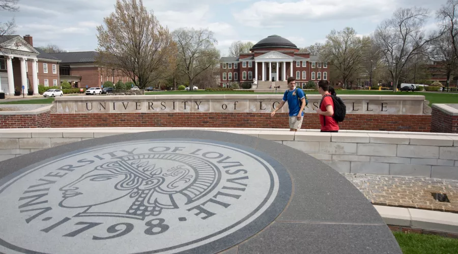 Students walking and talking near the 3rd Street entrance with Grawemeyer Hall and the School of Law buildings in the background