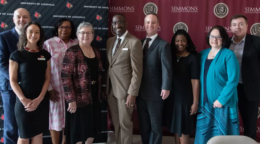 Group of researchers standing in front of UofL and Simmons College backdrops